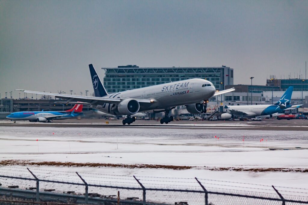 Aircraft flying over runway near airport building